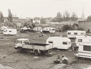 Black and white photograph of caravans parked on land with Worcester in the background.