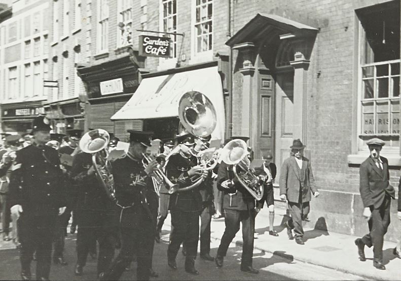 Brass band in uniform progressing down a street