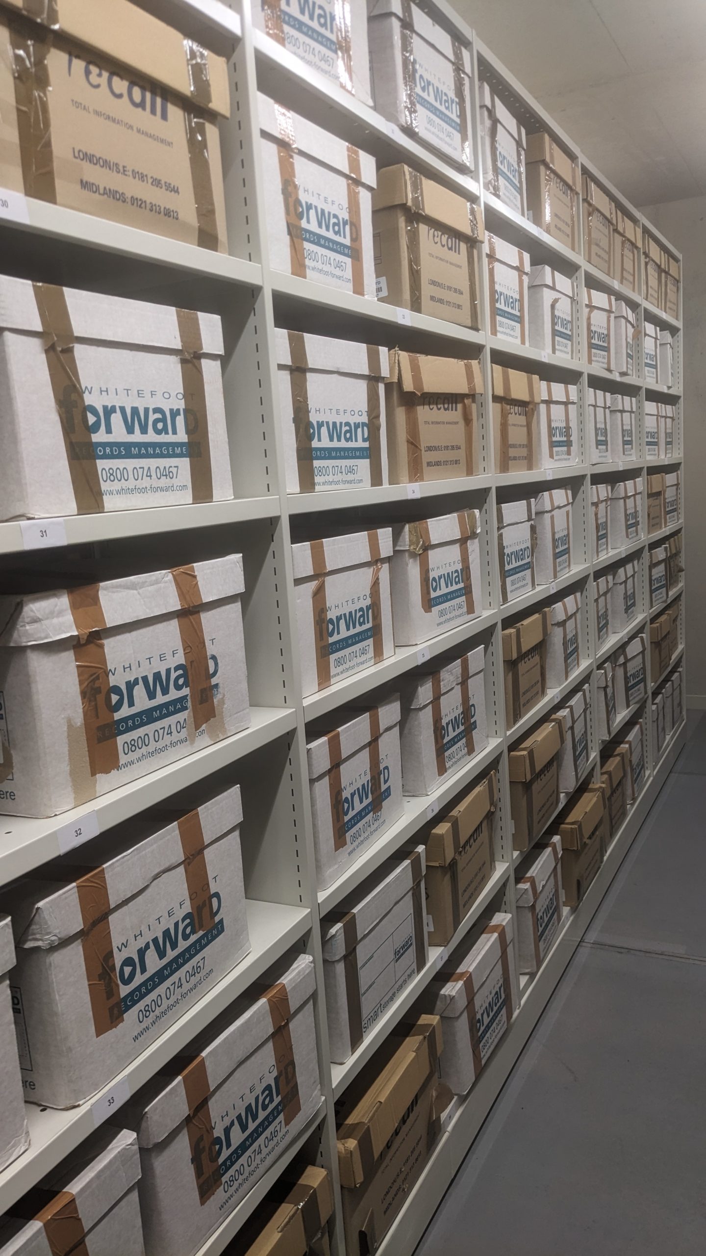 An image of many cardboard boxes on the shelves of patient files for Powick Hospital awaiting cataloguing in one of the archive service strong rooms. Copyright Worcestershire Archives and Archaeology Service.