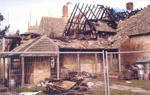 Fenced off building with part of the roof missing, leaving burnt timber rafters