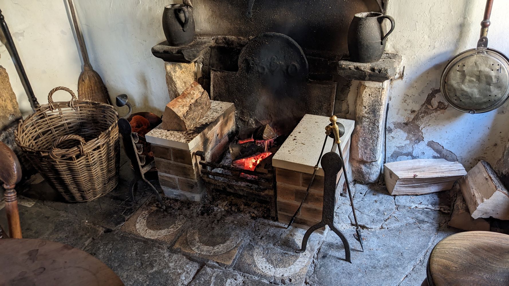 Photo of an old open fireplace with flagstone floor. On the floor by the fireplace are the outlines of three white circles.