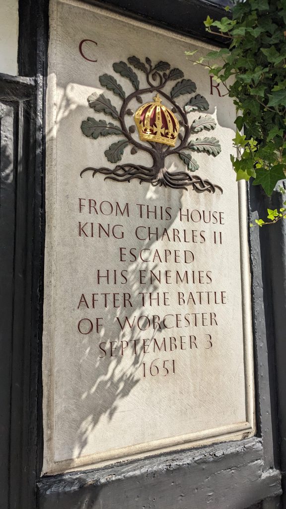 The image shows a colouful plaque on the outside of the King Charles Pub commemorating King Charles II's escape from King Charles House, New Street as it looks today. following its renovation in the 1960's