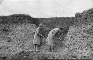 Two woman excavating a ditch.